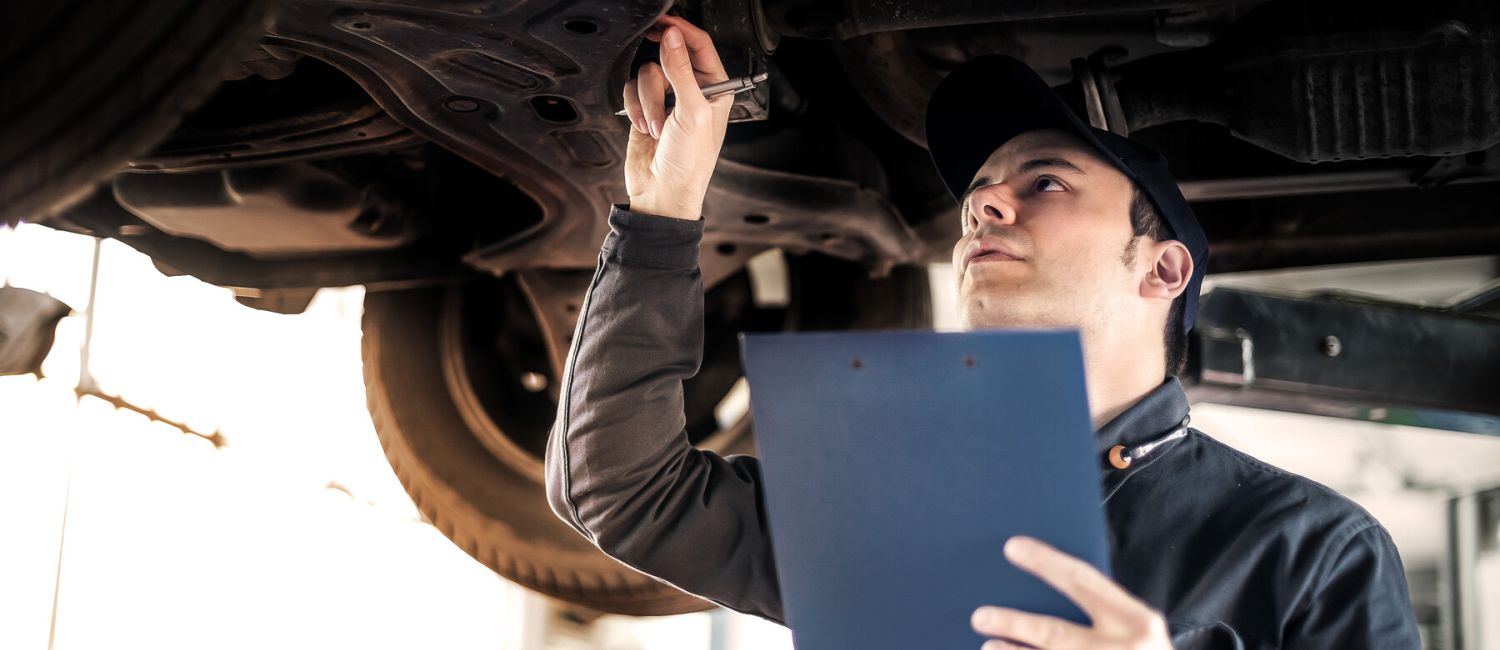 Symbolbild Prüfingieur unter einem PKW das auf einer Hebenbühne steht